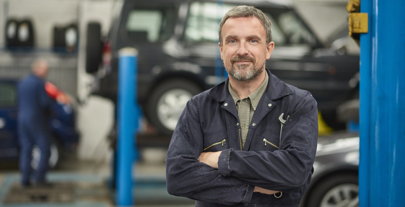 LifeStore Business loans. Garage owner in coveralls smiling and holding a wrench